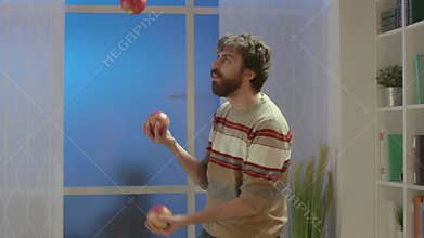 Man juggling with apples at home