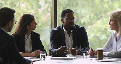 Motivated mixed race business people discussing project at brainstorming meeting.
