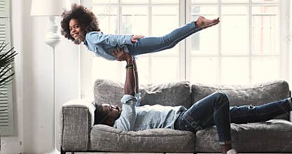 Positive biracial father enjoying gymnastics exercises with child.