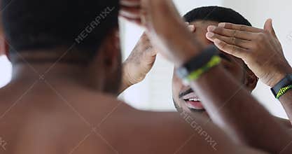 Close up happy mixed race man using skincare products.