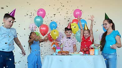 Children throw shiny confetti celebrating birthday at table