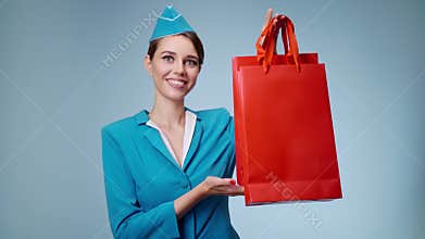 A charming flight attendant holds shopping bags in her hands. Duty free.