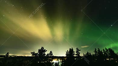 Winter Aurora Borealis green lights over city Umea and northern pine tree forest. Thin cold fog in air makes Northern Lights and