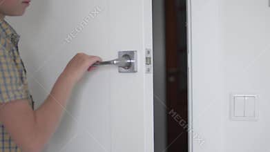 The boy opens and closes the door to the room
