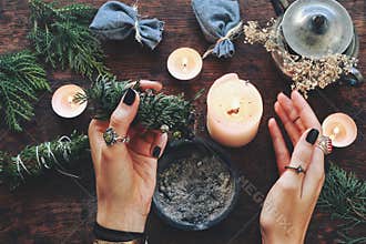 Wiccan witch holding cedar cleansing stick to cleanse the energy at her altar