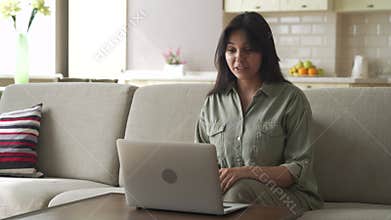 Smiling young indian woman video calling using laptop webcam conference at home.