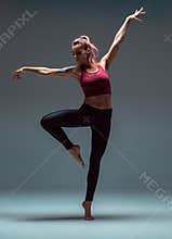 Stylish young woman dancing barefoot in studio isolated on gray background. Dance school poster