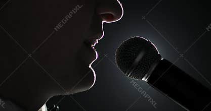 Politician man in suit is speaking microphone in spotlight, mouth closeup.