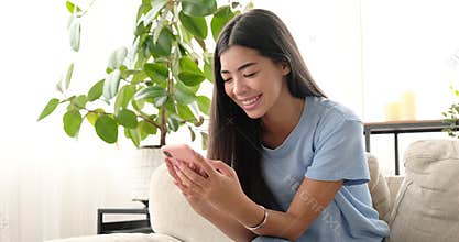 Happy woman chatting using mobile phone at home