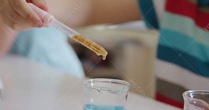 Girl wearing glasses using pipette and beaker