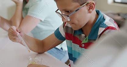 Girl wearing glasses using pipette and beaker