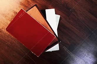 Four blank books stacked ontop of each other against a wooden background