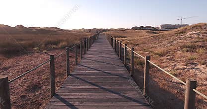 Walking along wooden boardwalk over sand dunes