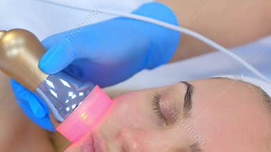 Portrait of woman on phonophoresis face procedure with hyaluronic acid gel.
