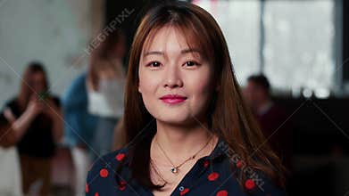 Portrait of beautiful young confident gen-z Asian IT business woman smiling at camera at modern busy office workplace.