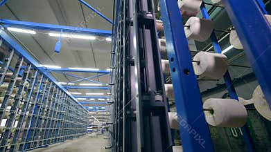 Clothing plant with bobbins getting unwound. Modern textile factory.