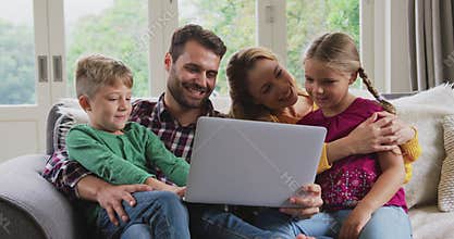 Family using laptop on the sofa in a comfortable home 4k