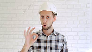 Engineer in hardhat gestures thumb up and ok.