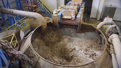 Liquid cellulose mixes in tank by wastepaper blocks in shop