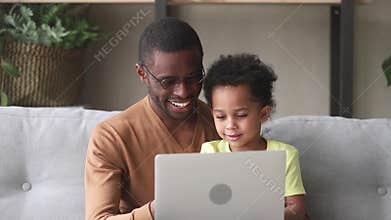 Happy black father teach kid son to read use laptop