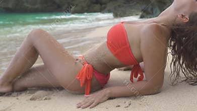 Beautiful woman relaxing on sandy beach on blue sea and cliff landscape. Attractive woman in bikini lying on sand at