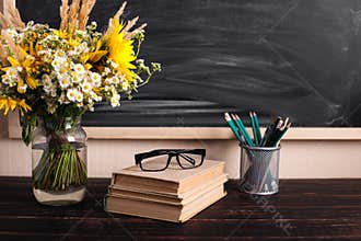 Teacher's day background. Black chalk board empty copy space and fresh wildflowers in vase. Holiday feminine poster.Spring