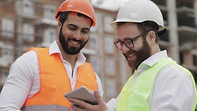 Smiling builder and architect man are discussing the construction plan of the modern business center standing near