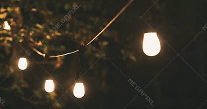 Mood lighting - party string lights swinging in slow wind at home garden