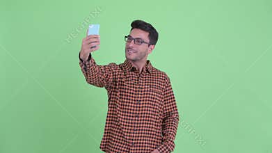 Happy young Hispanic hipster man taking selfie