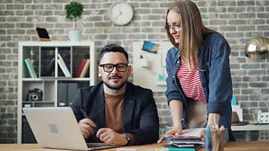 Businessman talking to assistant in office discussing work looking at laptop