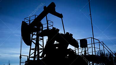Silhouette of a industrial oil pump jack pumping oil in field, oil business.