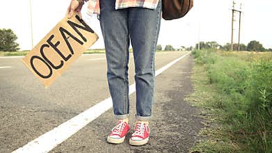 Young girl with a guitar coming along the road