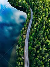 Aerial view of road between green forest and blue lake in Finland