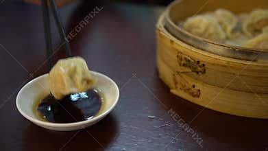 4K Dipping dumpling into soy sauce in restaurant. Traditional chinese food
