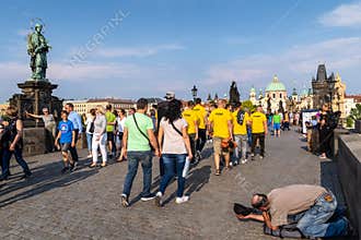 Tourists walking & posing for pictures while ignoring a begger in Charges Bridge, Prague