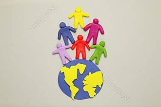 Plasticine multicolored cartoon people on globe. The use and depletion of the planet earth, overpopulation and population growth