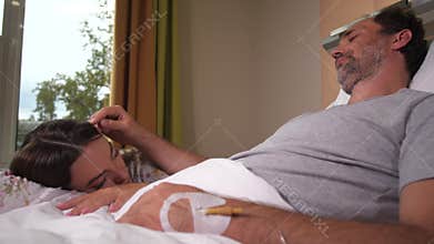 Loving married couple sleeping in hospital ward