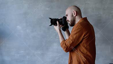 Young handsome photographer with a beard, taking pictures in the Studio on a professional camera. backstage