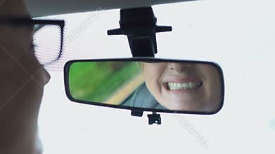 Aged woman looking at tooth in car mirror, massaging painful cheek, dental care