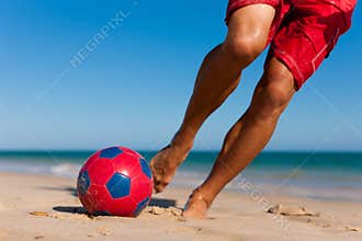 Man on beach balancing soccer ball