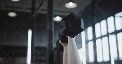 Close-up young beautiful Caucasian red haired athletic woman lifting dumbbells lying on bench in large professional gym.