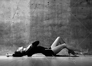 Tender sensual woman in little black dress is lying sexual posing on the floor touching her neck
