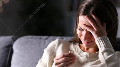 Sad wife complaining looking at ring after divorce