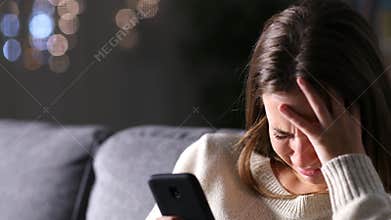 Sad woman reading phone content in the night