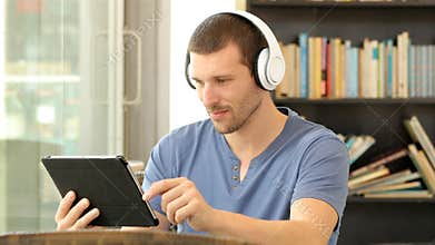 Man with headphones using a tablet in a bar