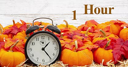 Fall Back 1 hour time change message with a retro alarm clock with pumpkins and fall leaves