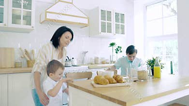 Two happy baby boys running to mom for breakfast in the kitchen