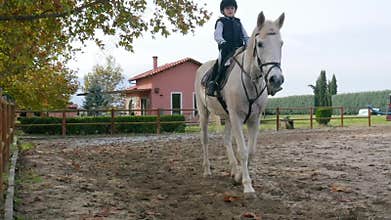 Kid learning to ride a horse on a ranch