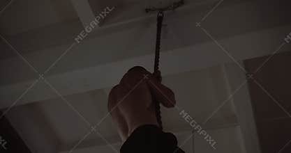 Young muscular athletic Caucasian man climbing rope, doing hardcore functional workout training in large gym slow motion