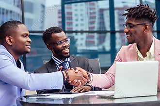 A group of three stylish African American businessman friends entrepreneurs fashion business suits meeting sitting at